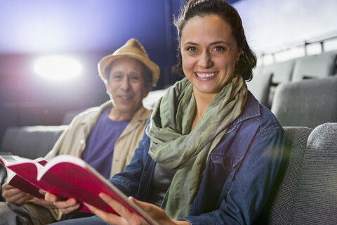 Porträt von kaukasischen Schauspielern, die mit Skripten im Theater im Publikum sitzen, lizenzfreies Stockfoto