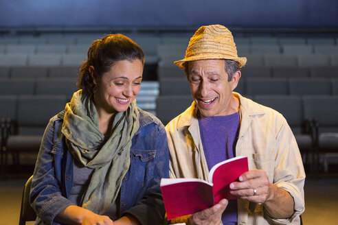 Caucasian actors rehearsing with script in theater - BLEF02544