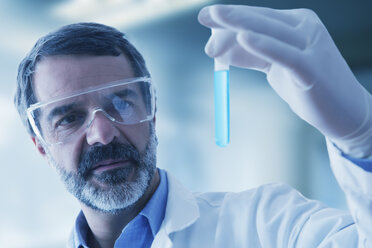 Hispanic researcher holding vial of blue liquid - BLEF02570