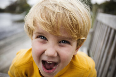 Playful Caucasian boy yelling on bench - BLEF02585