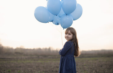Caucasian girl holding blue helium balloons - BLEF02595