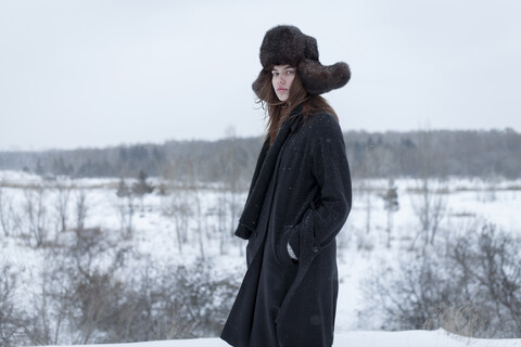 Ernste kaukasische Frau mit Pelzmütze und Mantel im Winter, lizenzfreies Stockfoto