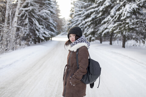 Asiatische Frau mit Rucksack auf verschneiter Straße, lizenzfreies Stockfoto