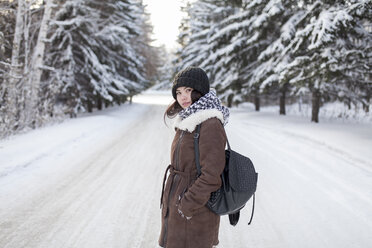 Asiatische Frau mit Rucksack auf verschneiter Straße - BLEF02618