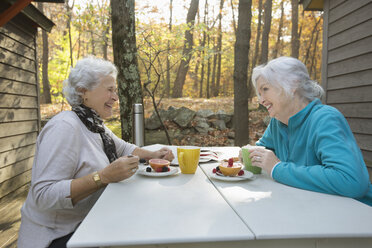 Caucasian women enjoying breakfast outdoors near cabin - BLEF02697