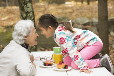 Großmutter und Enkelin spielen am Frühstückstisch im Freien - BLEF02701