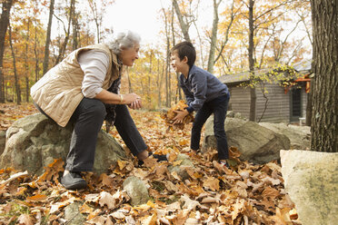 Grandmother and grandson playing with autumn leaves - BLEF02707