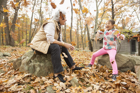 Grandmother and granddaughter playing with autumn leaves stock photo