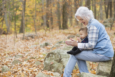 Grandmother playing with baby grandson in autumn - BLEF02713