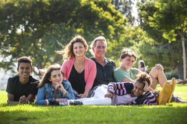 Porträt einer lächelnden Familie im Gras eines Parks - BLEF02754