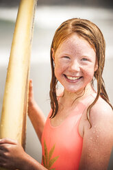 Portrait of smiling girl holding surfboard - BLEF02759