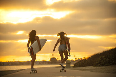 Teenager-Mädchen tragen Surfbretter auf Rollbrettern - BLEF02779