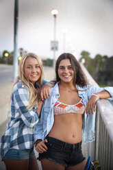 Portrait of smiling teenage girls leaning on railing - BLEF02796