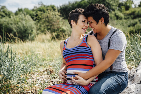 Schwangeres lesbisches Paar reibt sich im Freien die Nasen, lizenzfreies Stockfoto