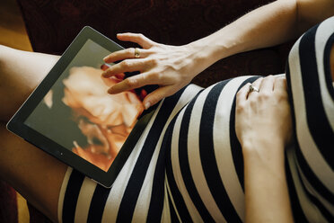 Mittelteil einer schwangeren kaukasischen Frau mit digitalem Tablet - BLEF02854