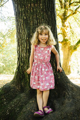 Porträt eines lächelnden kaukasischen Mädchens, das sich an einen Baum lehnt - BLEF02861