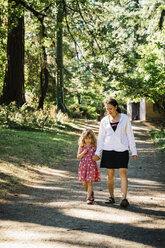 Kaukasische Mutter und Tochter gehen auf einem Weg im Park spazieren - BLEF02876