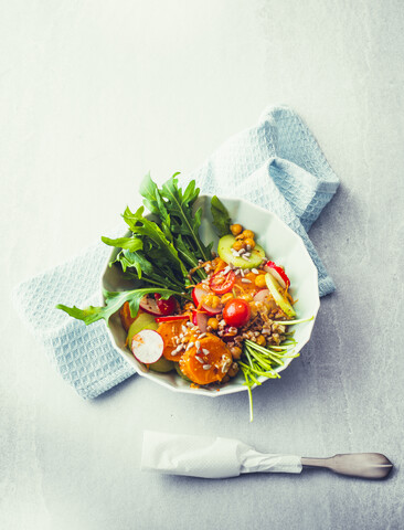 Gemüse-Poke Bowl mit Dinkel, Kichererbsen, Rettich, Rucola und Süßkartoffeln, lizenzfreies Stockfoto