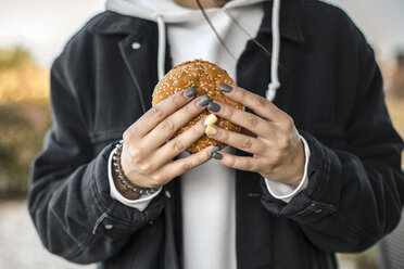 Hände einer jungen Frau mit lackierten Nägeln, die einen Hamburger halten, Nahaufnahme - ACPF00505