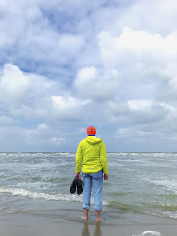 Belgien, Flandern, Nordsee, Mann steht barfuß in den Wellen, entspannt sich und beobachtet die Wellen, lauscht dem Meeresrauschen, lizenzfreies Stockfoto