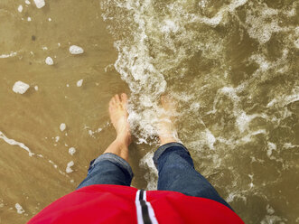 Belgien, Flandern, Nordsee, Frau steht barfuß am Strand in den Wellen des Meeres - GWF06075