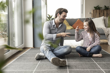 Young man and little girl sitting at home, playing paper scissors stone - UUF17312