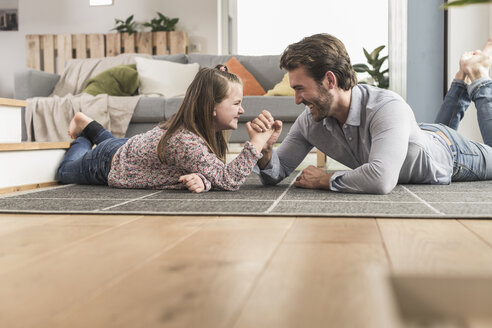 Junger Mann und kleines Mädchen liegen auf dem Boden und ringen mit den Armen - UUF17323