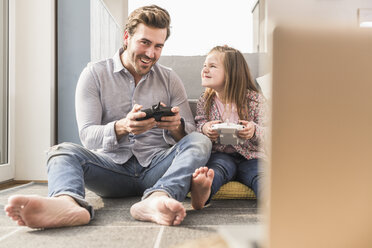 Young man and little girl playing computer game with gaming console - UUF17334