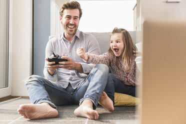 Young man and little girl playing computer game with gaming console - UUF17335