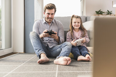 Young man and little girl playing computer game with gaming console - UUF17336