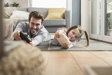 Young man and little girl playing computer game with gaming console - UUF17339