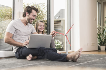 Young man and little girl playing with model of a wind turbine - UUF17358