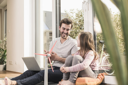 Young man and little girl playing with model of a wind turbine - UUF17360
