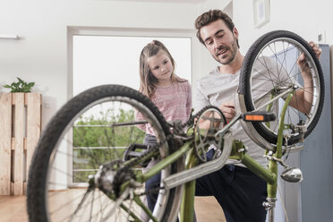 Young man and little girl repairing bicycle together - UUF17365