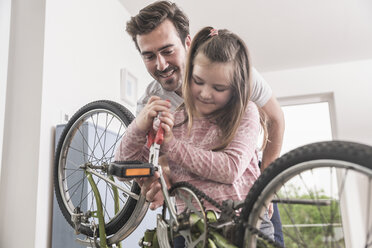 Young man and little girl repairing bicycle together - UUF17366