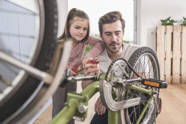 Young man and little girl repairing bicycle together - UUF17367