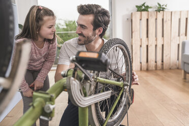 Young man and little girl repairing bicycle together - UUF17369