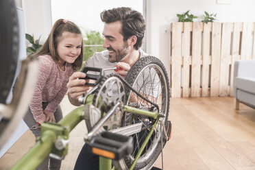 Young man and little girl repairing bicycle together - UUF17370