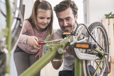 Young man and little girl repairing bicycle together stock photo