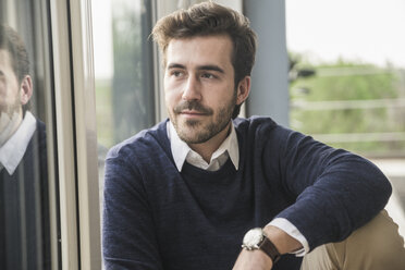 Portrait of a young businessman sitting by the window - UUF17383