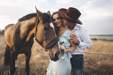 Caucasian cowboy kissing woman on cheek near horse - BLEF02884