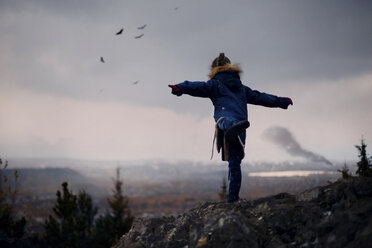 Kaukasisches Mädchen balanciert auf Felsen und ahmt fliegende Vögel nach - BLEF02954