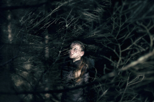 Kaukasisches Teenager-Mädchen hinter Baumzweigen bei Nacht - BLEF02961