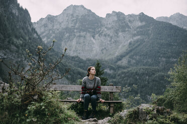 Kaukasische Frau sitzt auf einer Bank in den Bergen - BLEF02981