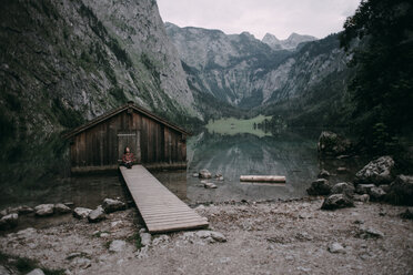 Kaukasische Frau sitzt auf dem Steg einer abgelegenen Hütte - BLEF02985