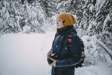 Kaukasische Frau hält Kamera im verschneiten Wald - BLEF02993