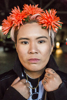 Porträt einer ernsten androgynen asiatischen Frau mit Blumen im Haar - BLEF03032