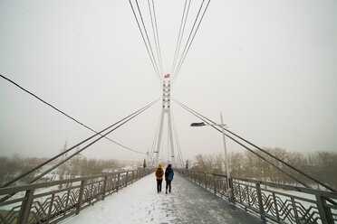 Caucasian women crossing bridge in winter - BLEF03041