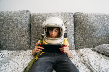 Junge, der ein Videospiel auf einer Spielkonsole spielt und einen Weltraumhut trägt - JCMF00051
