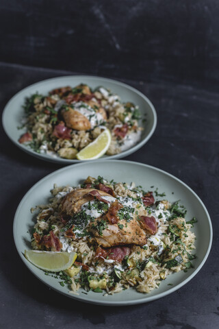 Cajun-Hähnchen mit Speck, Zucchini-Zitronen-Reis und Joghurtsauce, lizenzfreies Stockfoto